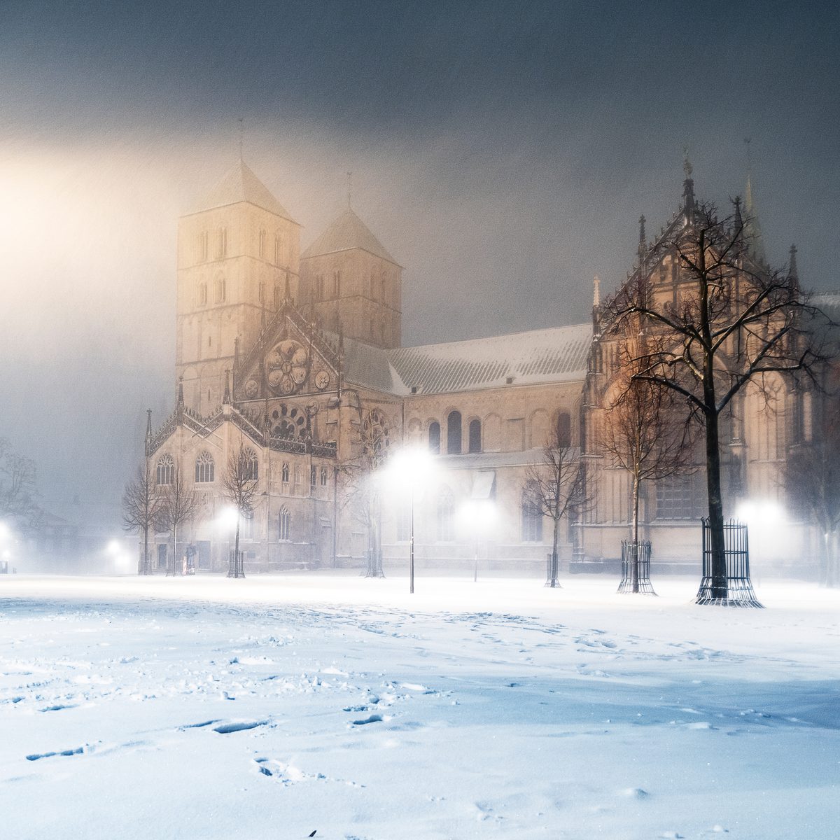 Der St.-Paulus-Dom im Nebel, davor der verschneite Domplatz mit leuchtenden Laternen
