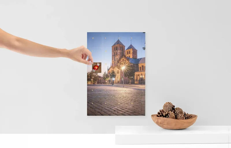 Foto-Adventskalender mit dem Motiv Dom bei Nacht, eine Hand öffnet ein Türchen