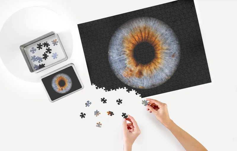 Irisbild als Puzzle, daneben die Schachtel und einzelne Puzzleteile