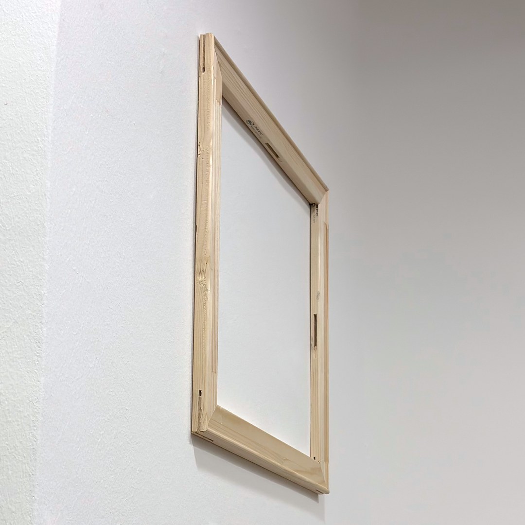 Leerer Holzkeilrahmen hängt schräg an einer weißen Wand: die Eckverbindung und die Bautiefe des Trägerrahmens sind zu sehen