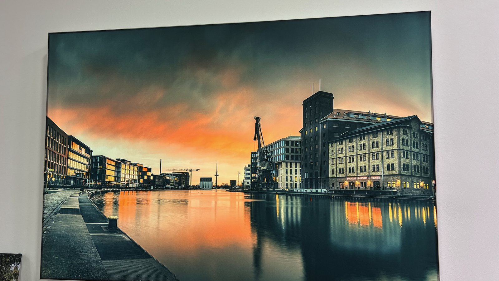 Eingeschaltetes Leuchtbild an der Wand im Ladenlokal: der Münsteraner Stadthafen mit dem Wolfgang-Borchert-Theater im Sonnenuntergang (Motiv: © Sascha Talke)