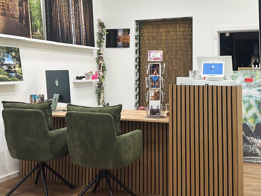 Beratungsplatz im Ladenlokal: zwei grüne Sessel an der Lamellentheke mit Bildschirm und Kartenständer, ringsum Wandbilder – hier besprechen wir Ihr eigenes Foto