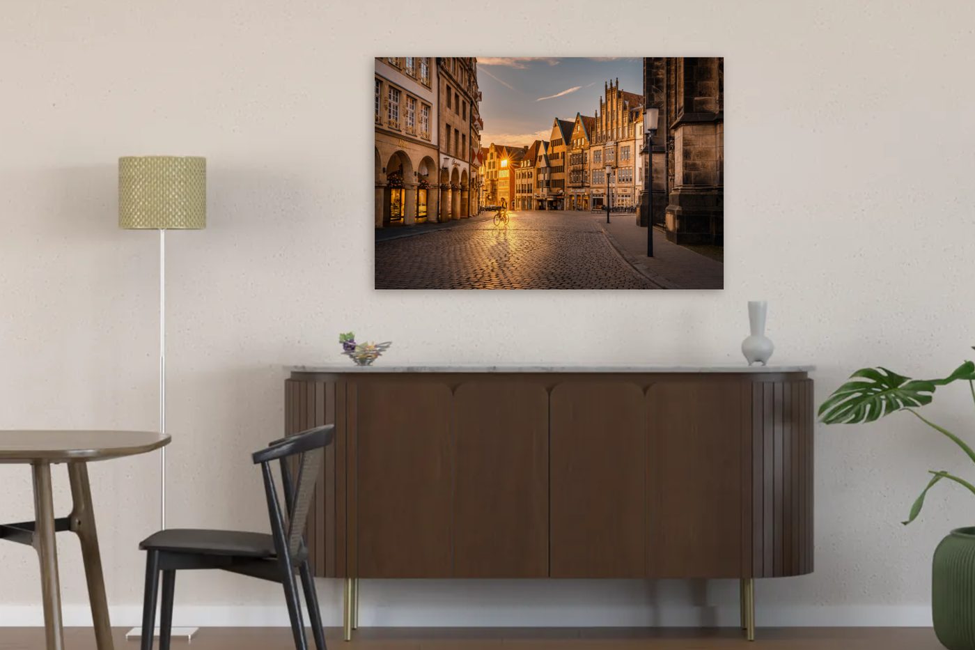 Visualisierung: Wandbild vom Prinzipalmarkt in Münster in der goldenen Stunde über einem dunklen Sideboard im Esszimmer, links Esstisch und Stuhl